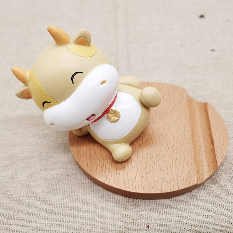 Cute cartoon cow figurine on a wooden stand with a plain background