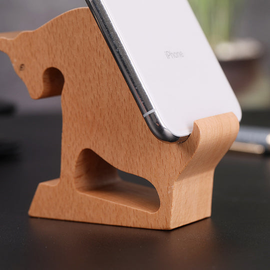 Wooden phone stand holding a smartphone on a dark surface