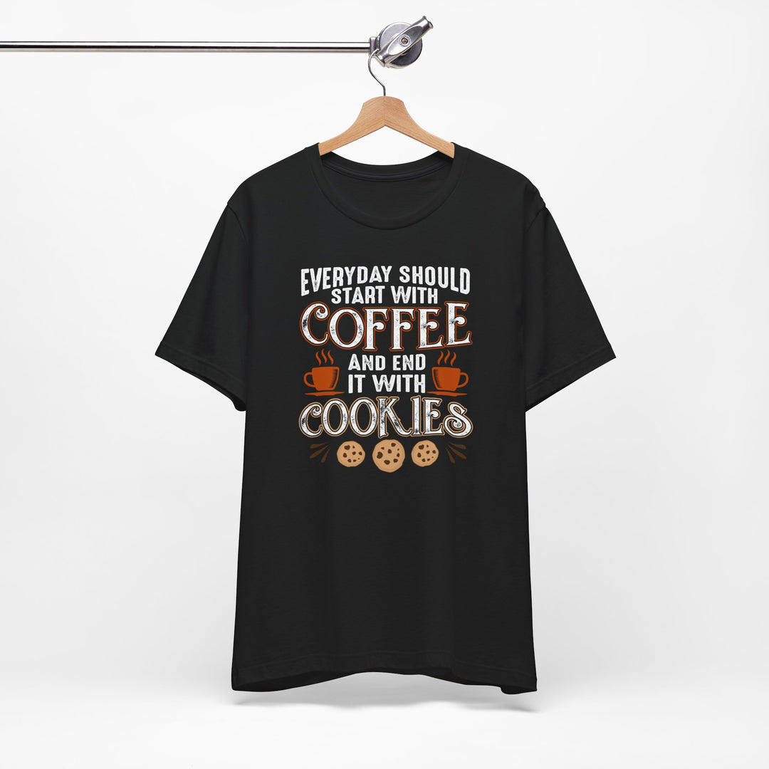 Black t-shirt with coffee and cookies graphic on a hanger against a white background