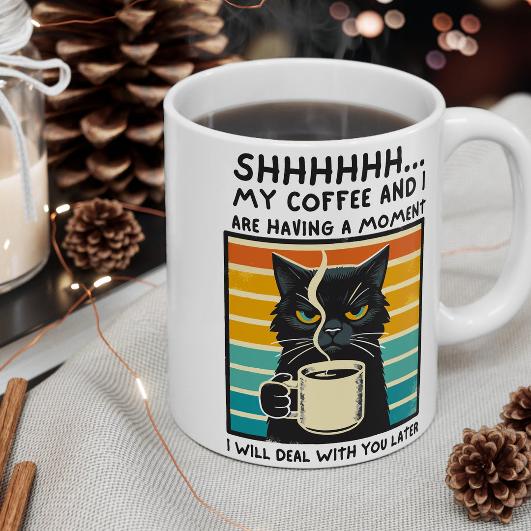 Mug with a cat design and text about coffee and a moment, surrounded by decorative items.