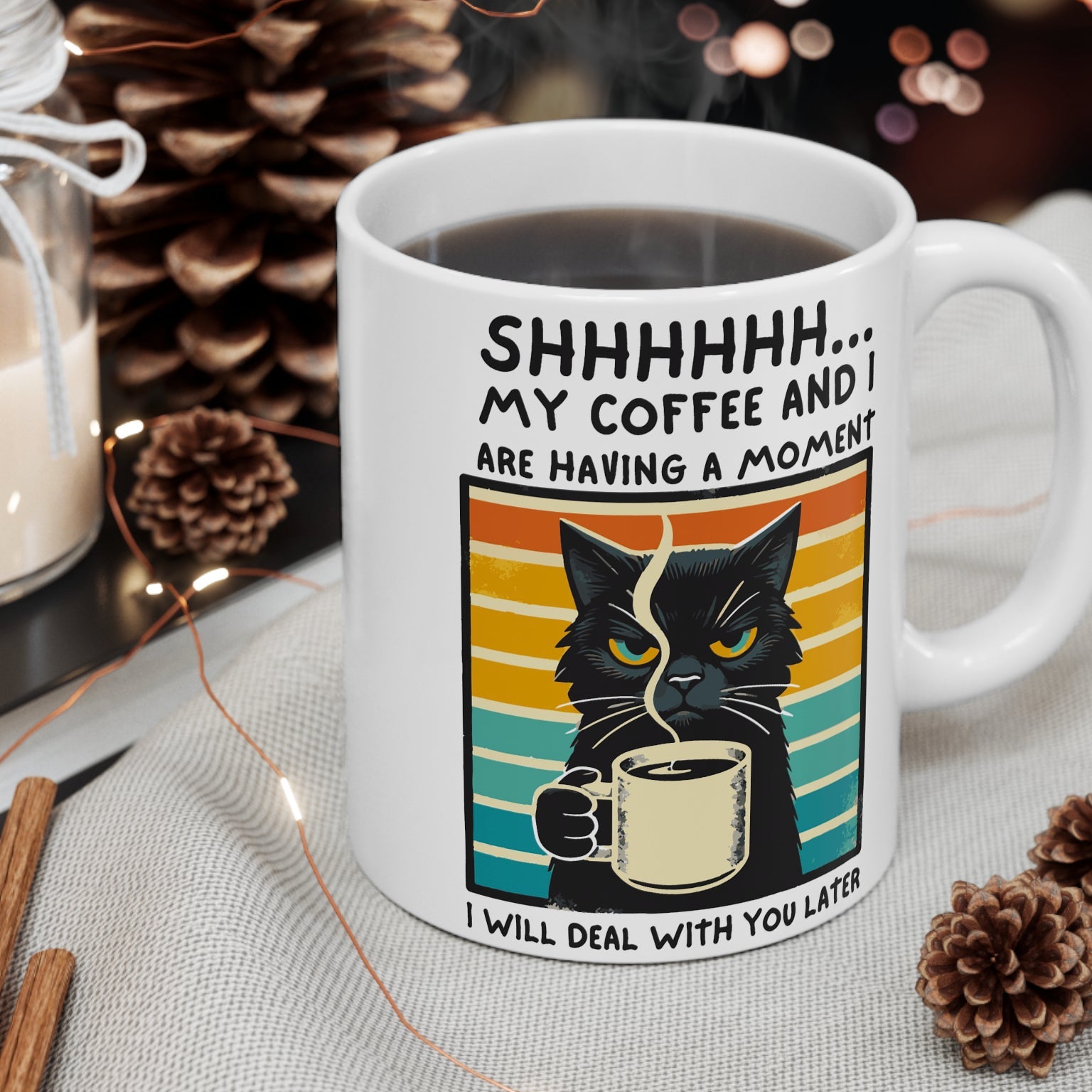 Mug with a cat design and text about coffee and a moment, surrounded by decorative items.