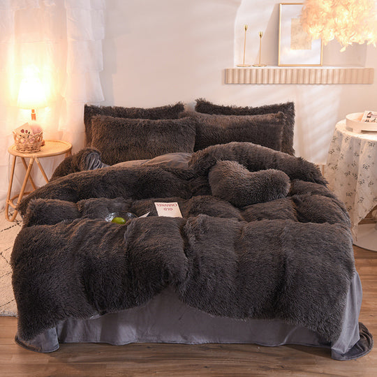 Fluffy dark gray comforter on a bed in a bedroom setting with soft lighting.
