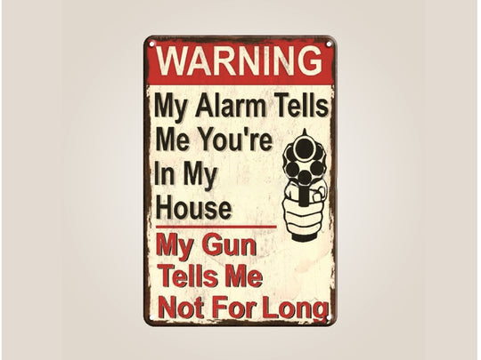 Metal sign with humorous warning text and a gun graphic on a beige background