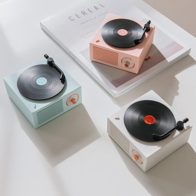 Three miniature record players in different colors on a light surface.