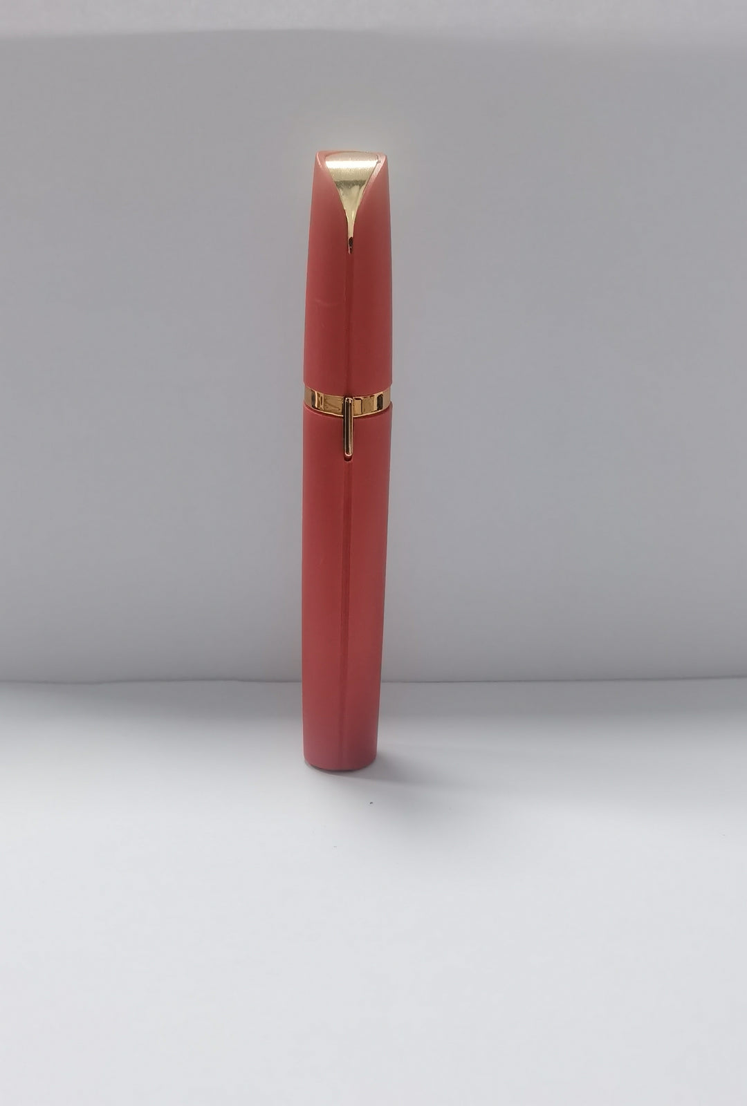 Red lipstick with gold accents on a light gray background