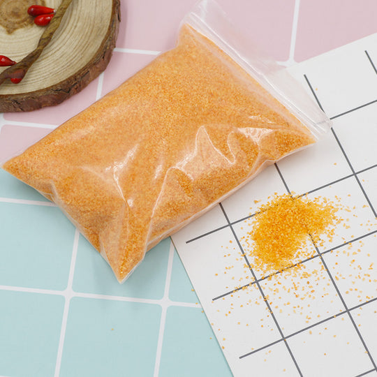 Clear bag of yellow beads on a tiled surface with scattered beads.