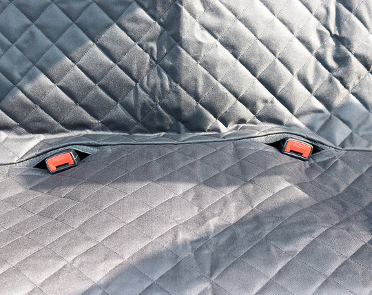 Gray quilted car mat with red clips on a textured surface