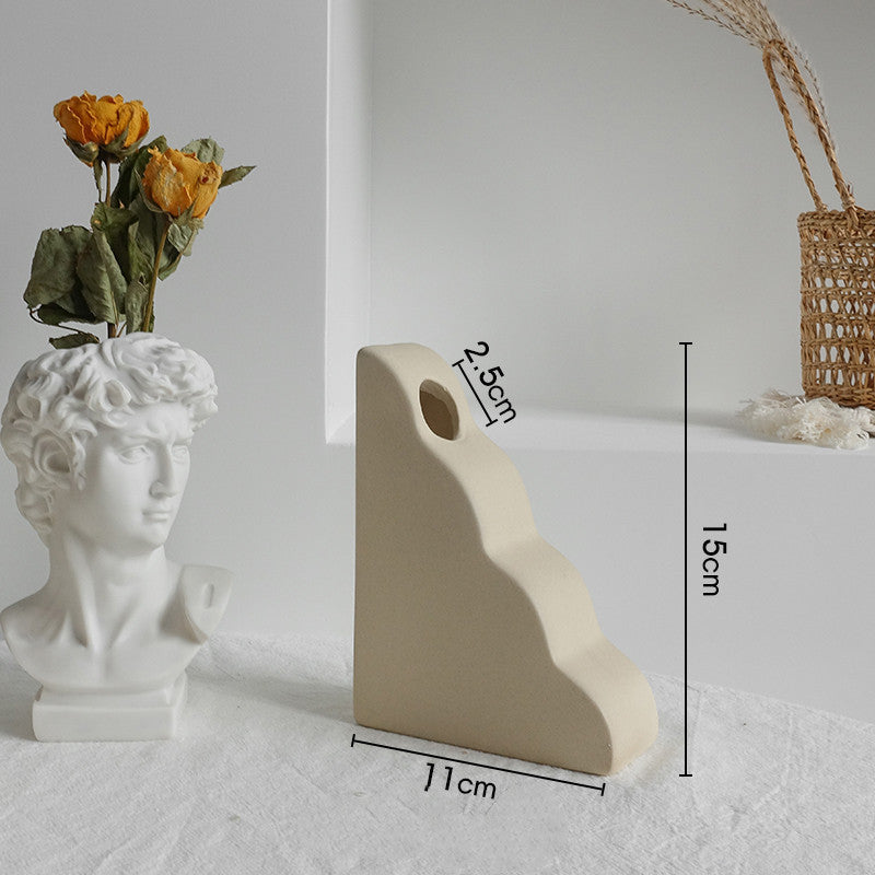 White stone sculpture of a bust with dried flowers and measurements on a light gray background
