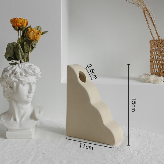 White stone sculpture of a bust with dried flowers and measurements on a light gray background