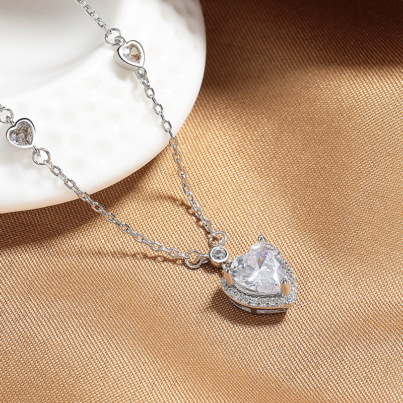 Silver necklace with a heart-shaped pendant on a beige fabric background
