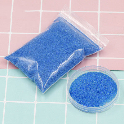 Blue sand in a clear plastic bag and container on a pink and blue checkered background