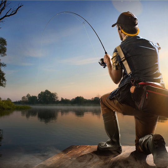 Man fishing on a dock at sunset with calm water and trees in the background