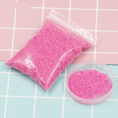 Pink beads in a clear plastic bag and container on a checkered background