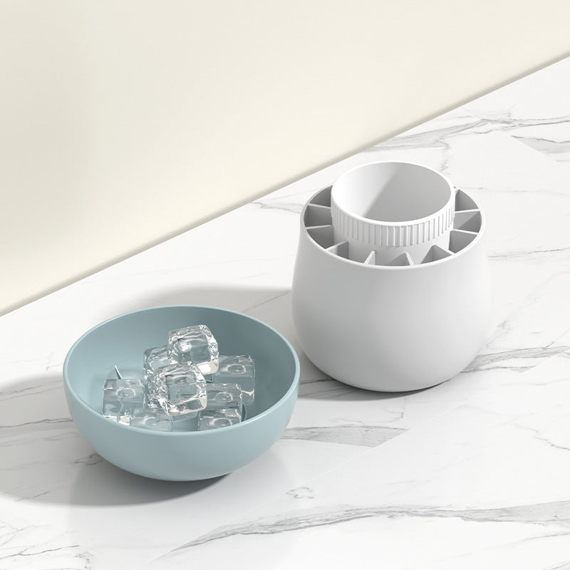 Light blue bowl with ice cubes and white ice cube tray on a marble surface