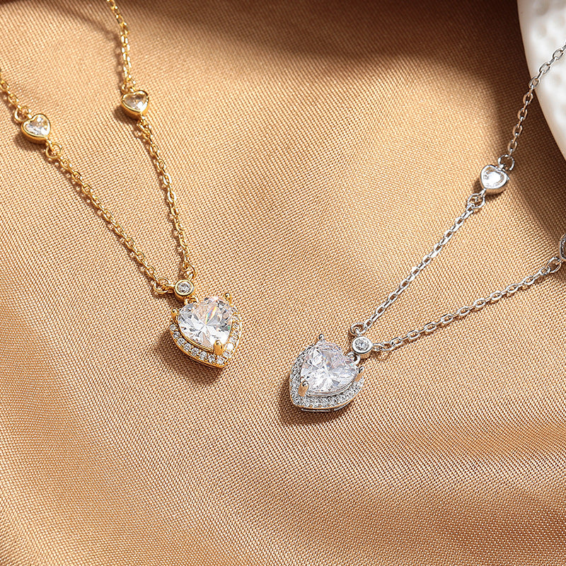 Two heart-shaped diamond pendants on gold and silver chains on a beige fabric background.