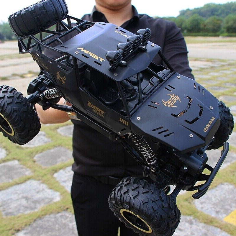 Black remote-controlled off-road vehicle held by a person outdoors