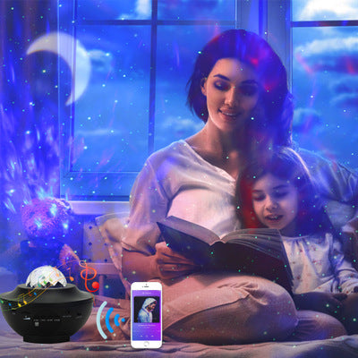 Woman and child reading a book with a starry night light projector on a table.