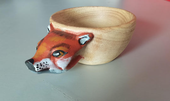 Wooden bowl with a fox face design on a light background