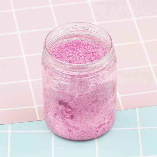 Pink bath bomb in a glass jar on a pink and blue tiled background