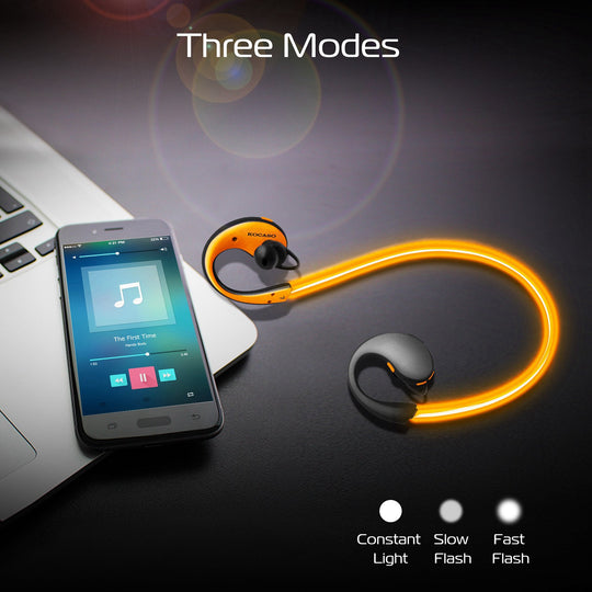 Wireless earbuds with smartphone displaying music app on a dark surface