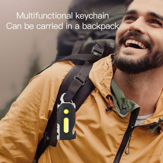 Man wearing a yellow jacket with a multifunctional keychain attached to his backpack.