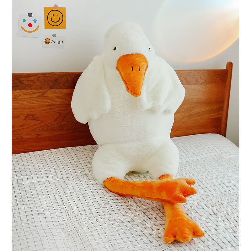 Large plush duck toy on a bed with a wooden headboard.