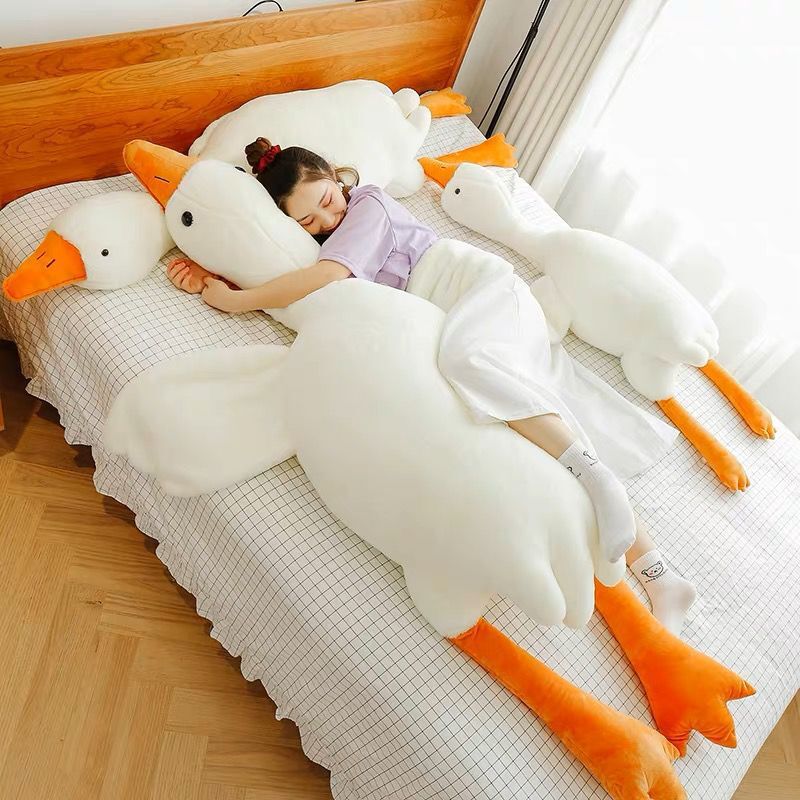 Person lying on a bed with large goose-shaped pillows