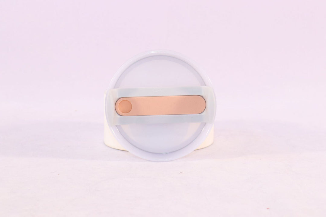 Clear container with a gold-colored object on a light purple background