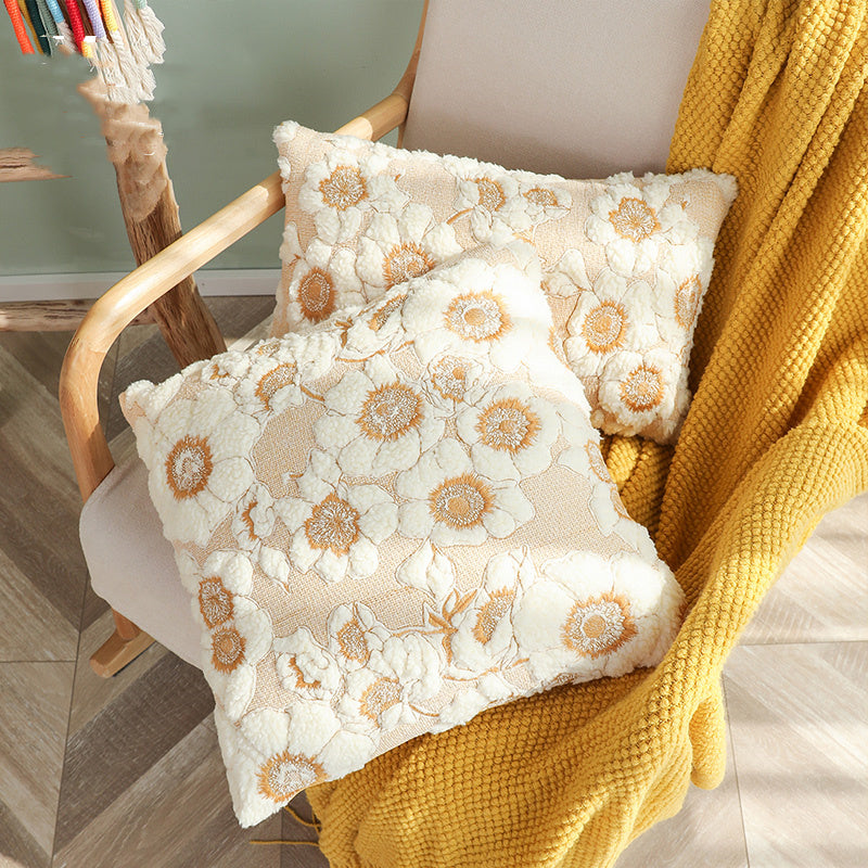 Floral-patterned pillows on a chair with a yellow blanket