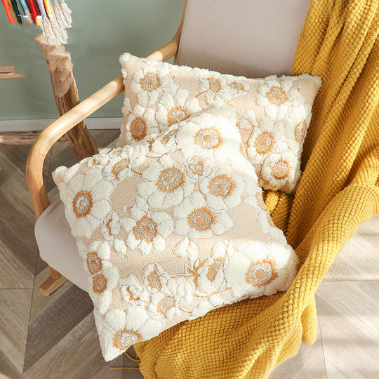 Floral-patterned pillows on a chair with a yellow blanket