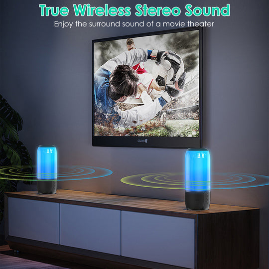 Two blue and black speakers on a wooden cabinet with a TV displaying a movie scene in the background.