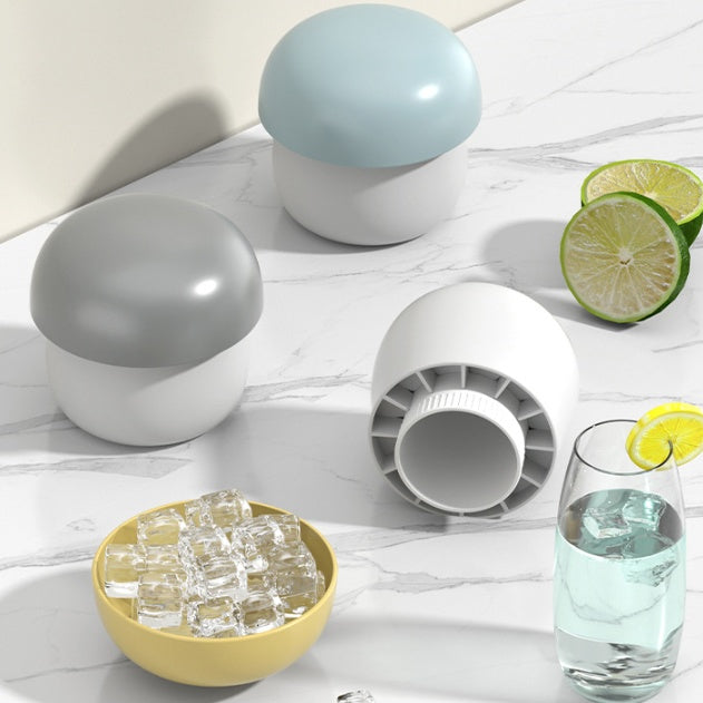 Ice cube tray with spherical silicone molds, ice cubes, and a glass of water on a light wooden surface.