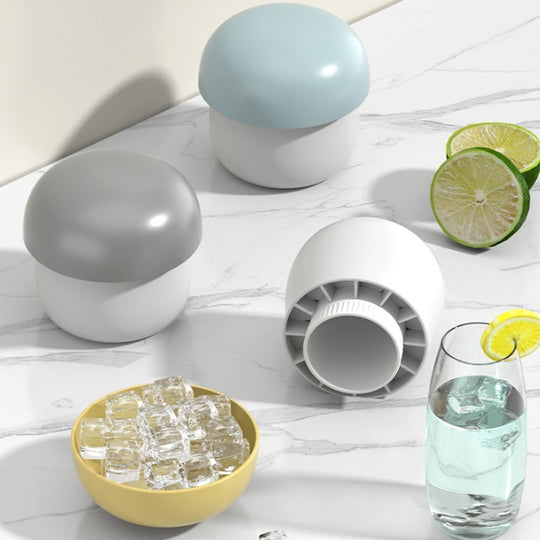 Ice cube tray with spherical silicone molds, ice cubes, and a glass of water on a light wooden surface.