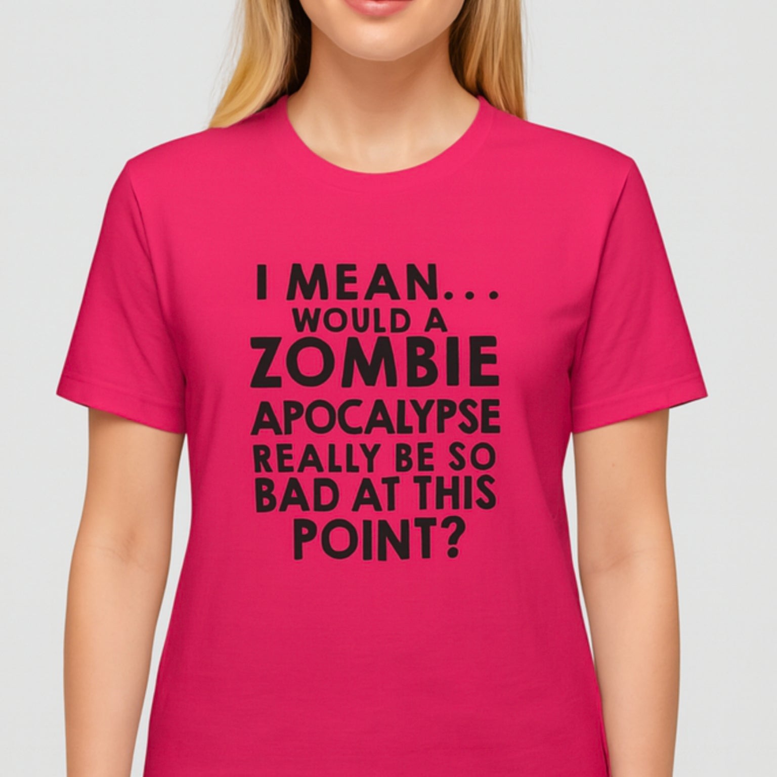 Person wearing a pink t-shirt with a humorous zombie apocalypse joke on a plain background