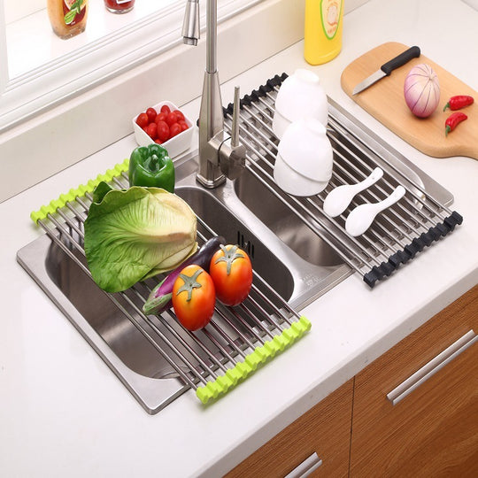 Stainless steel kitchen sink with a drying rack holding vegetables and dishes.