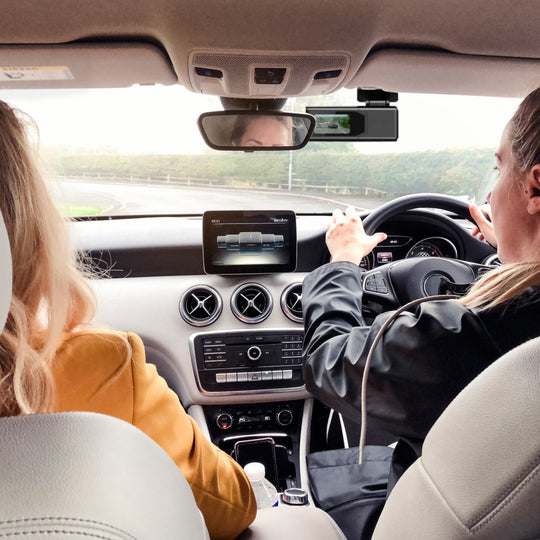 Two women in a car, one driving and one sitting next to her, with a focus on the car&