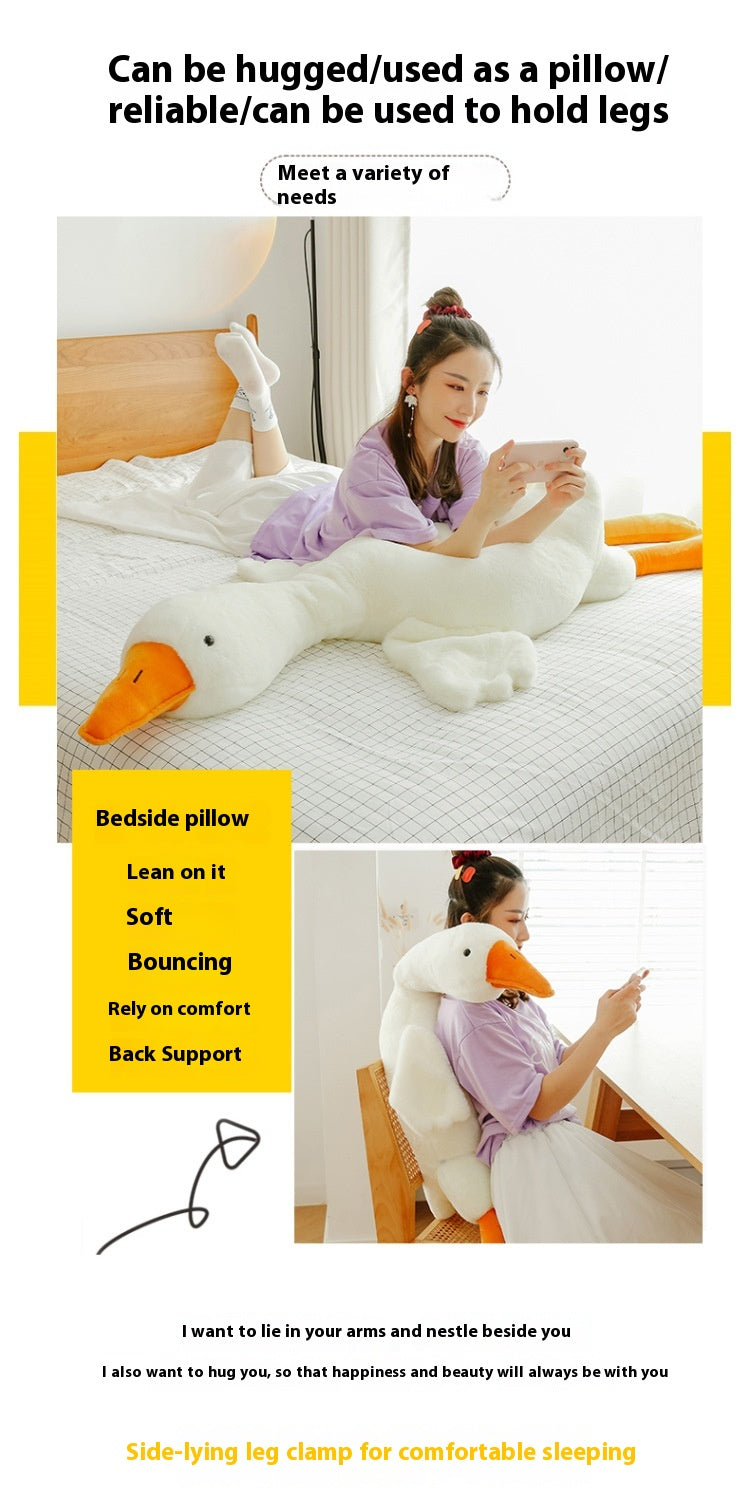 Large plush duck pillow being used as a pillow and support for legs on a bed.