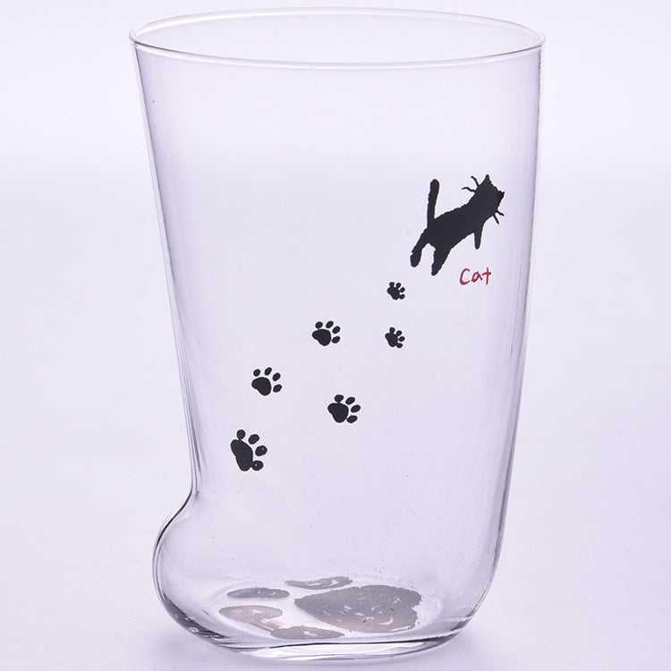 Clear glass tumbler with black paw prints and a cat illustration on a light purple background