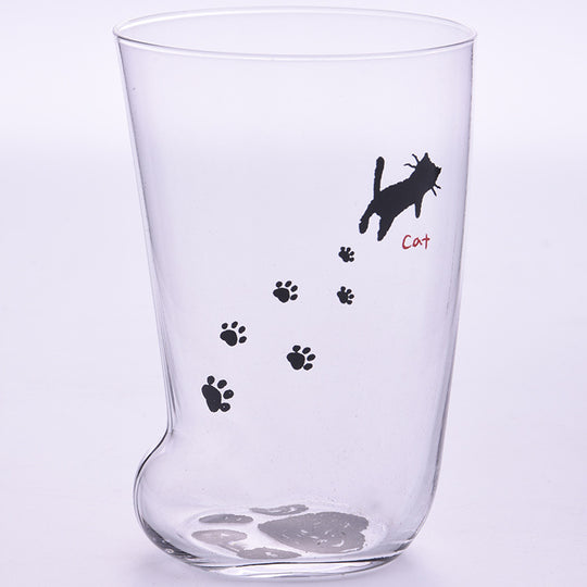 Clear glass tumbler with black paw prints and a cat illustration on a light purple background
