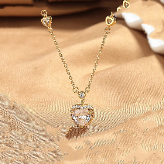 Gold necklace with a heart-shaped pendant on a beige fabric background