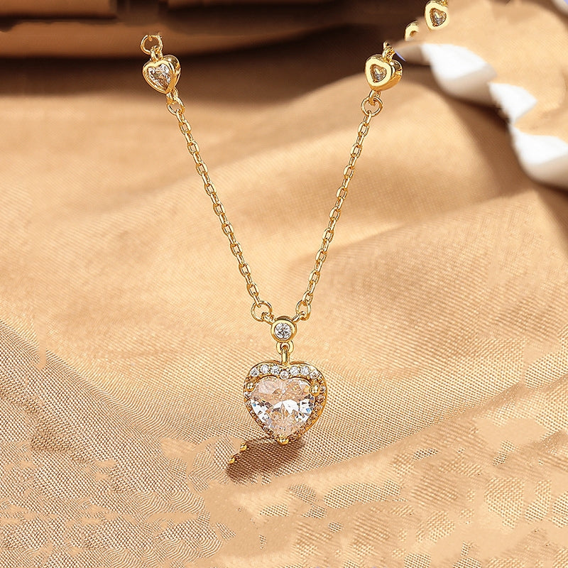 Gold necklace with a heart-shaped pendant on a beige fabric background