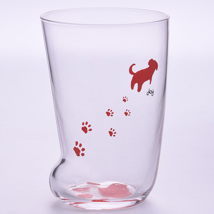 Clear glass tumbler with red dog illustration and paw prints on a light purple background