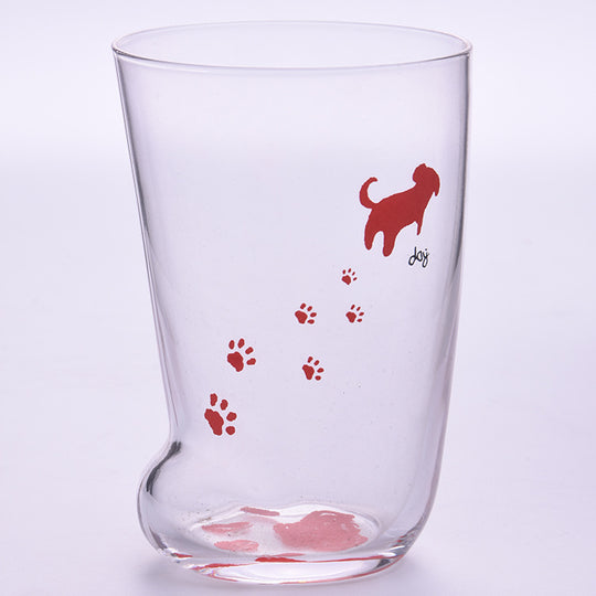 Clear glass tumbler with red dog illustration and paw prints on a light purple background