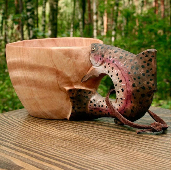 Wooden bowl with a fish design on a wooden surface outdoors