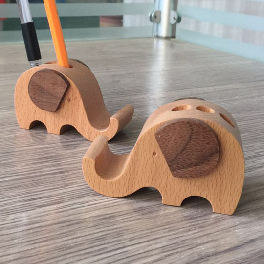 Two wooden elephant-shaped pencil holders on a wooden surface.