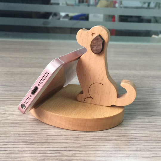 Wooden phone stand shaped like a dog with a smartphone on a wooden surface
