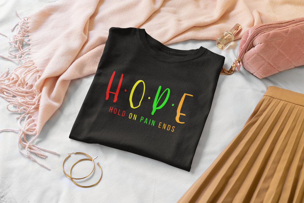 Black t-shirt with colorful 'HOPE' text on a light surface with accessories.