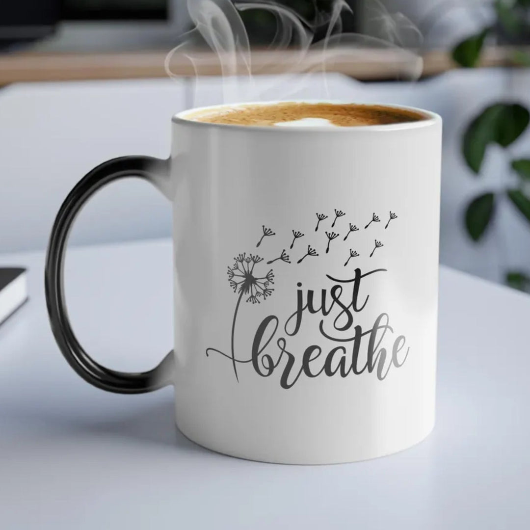 Mug with 'just breathe' text on a desk with a laptop and plant in the background