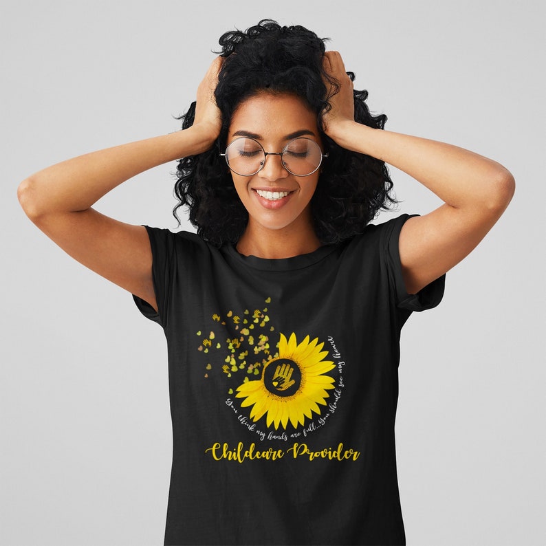 Woman wearing a black t-shirt with a sunflower design and text on a gray background