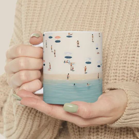 Person holding a mug with a beach scene design